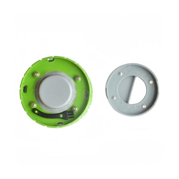 A green plastic cap with internal components sits next to a gray plastic cover with screw holes.