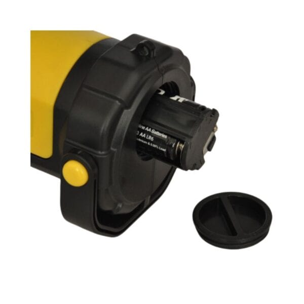 Close-up of a device with its battery compartment open, exposing AA batteries inside. The cover is placed next to the device.