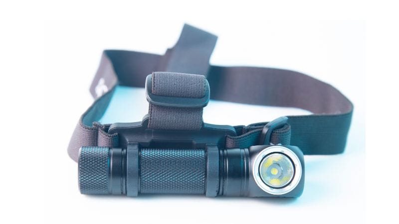 Lampe frontale LED noire avec sangle réglable repose sur un fond blanc.
