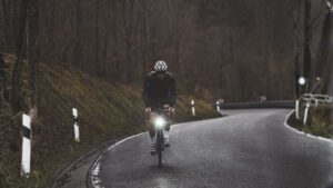 Bright cyclist riding on mountain road during cloudy weather, wearing helmet, for outdoor sports and cycling activity.