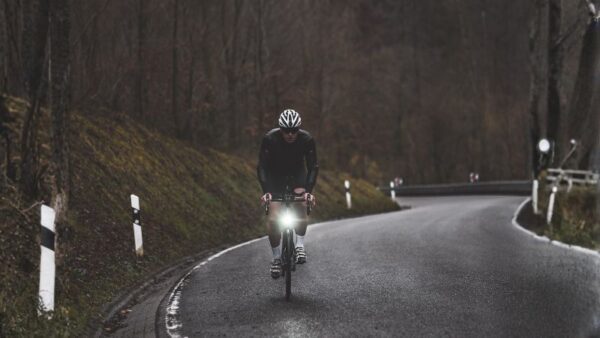 Bright cyclist riding on mountain road during cloudy weather, wearing helmet, for outdoor sports and cycling activity.